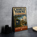 A vintage-style sign for Charles Towne Landing, a historic site in South Carolina, featuring an illustration of a coastal scene with palm trees and a ship.