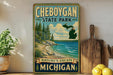 A vintage-style sign for Cheboygan State Park, featuring a scenic illustration of a lake, mountains, and pine trees.