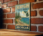 A vintage-style metal sign for Cheboygan State Park, featuring a scenic image of the park's natural landscape.