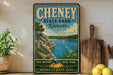 A vintage-style sign for Cheney State Park in Kansas, featuring a scenic landscape with a lake, mountains, and a sailboat.