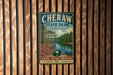 A vintage-style metal sign for Cheraw State Park in South Carolina, featuring a scenic image of a river, pine trees, and a bridge.