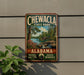 A vintage-style metal sign for Chewala State Park in Alabama, featuring a scenic landscape with a river, trees, and a waterfall.
