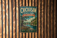 A vintage metal sign for Chickasaw State Park in Alabama, featuring a scenic illustration of a river, trees, and a bridge.