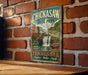 A vintage-style metal sign for Chickasaw State Park in Tennessee, featuring a scenic image of a waterfall surrounded by trees and a bridge.