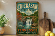 A vintage-style sign for Chickasaw State Park in Tennessee, featuring a scenic image of a waterfall surrounded by lush greenery.