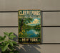 A metal sign with a scenic image of a pond and trees, mounted on a wall next to a plant.