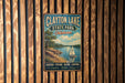 A vintage metal sign for Clayton Lake State Park in Oklahoma, featuring a scenic image of a lake with a sailboat, surrounded by trees and mountains.