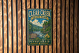 A vintage metal sign for Clear Creek State Park in Pennsylvania, featuring a scenic illustration of the park's natural surroundings.