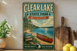 a vintage-style sign for Clear Lake State Park, Michigan, with a scenic illustration of a lake, trees, and a canoe.