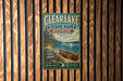 A vintage metal sign for Clear Lake State Park in Michigan, featuring a canoe on a lake surrounded by pine trees.