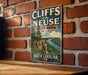 A vintage metal sign for Cliffs of the Neuse State Park in North Carolina, featuring a scenic illustration of the park's cliffs and surrounding landscape.
