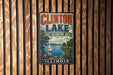 A vintage metal sign for Clinton Lake, Illinois, featuring a sailboat on the lake and a scenic landscape.