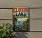 A vintage-style sign for Clinton Lake, Illinois, featuring a scenic image of the lake and surrounding landscape.