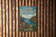 A vintage metal sign for Clyde Holiday State Recreation Site in Oregon, featuring a scenic landscape with a river, mountains, and a sign indicating boating, fishing, and camping opportunities.