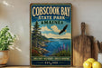 A vintage-style metal sign for Cobscook Bay State Park in Maine, featuring a scenic landscape with a bald eagle in flight, pine trees, and a body of water.