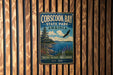 A vintage metal sign for Cobscook Bay State Park in Maine, featuring a scenic landscape with a pine tree, a bird in flight, and a body of water.