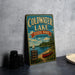 A vintage metal sign for Coldwater Lake State Park in Michigan, featuring a scenic illustration of a lake, boat, and surrounding landscape.