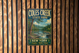 A vintage-style metal sign for Coles Creek State Park, featuring a scenic landscape with a river, trees, and mountains.