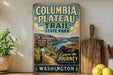 A vintage-style sign for Columbia Plateau Trail in Washington State Park, featuring a scenic mountain landscape and a trail sign.