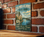 A vintage-style sign for Columbus-Belmont State Park, featuring a scenic image of a river and mountains, mounted on a brick wall.