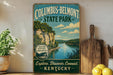A vintage-style sign for Columbus-Belmont State Park, featuring a scenic image of a river and cliffs, with the text "Columbus-Belmont State Park" and "Explore. Discover. Connect. Kentucky" printed on it.