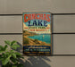 A vintage-style sign for Conchas Lake State Park in New Mexico, featuring a scenic image of the lake and mountains.