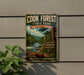 A vintage-style metal sign for Cook Forest State Park in Pennsylvania, featuring a scenic image of a river, pine trees, and a canoe.