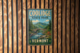 A vintage metal sign for Coolidge State Park in Vermont, featuring a scenic landscape with a bridge and mountains in the background.