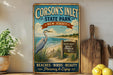A vintage-style metal sign for Corson's Inlet State Park, featuring a seagull, beach, and wildlife sign, with a wooden paddle and lemons on a shelf in the background.