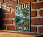 A vintage-style metal sign for Cove Lake State Park in Tennessee, featuring a scenic illustration of the lake and surrounding landscape.