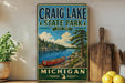 A vintage-style metal sign for Craig Lake State Park in Michigan, featuring a scenic image of a canoe on the lake and pine trees in the background.