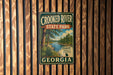A vintage metal sign for Crooked River State Park in Georgia, featuring a scenic illustration of a river and forest.