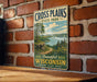 A vintage metal sign for Cross Plains State Park in Wisconsin, featuring a scenic landscape with a lake and forest.