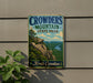 A vintage metal sign for Crowders Mountain State Park in North Carolina, featuring a scenic mountain landscape with a river and lush vegetation.