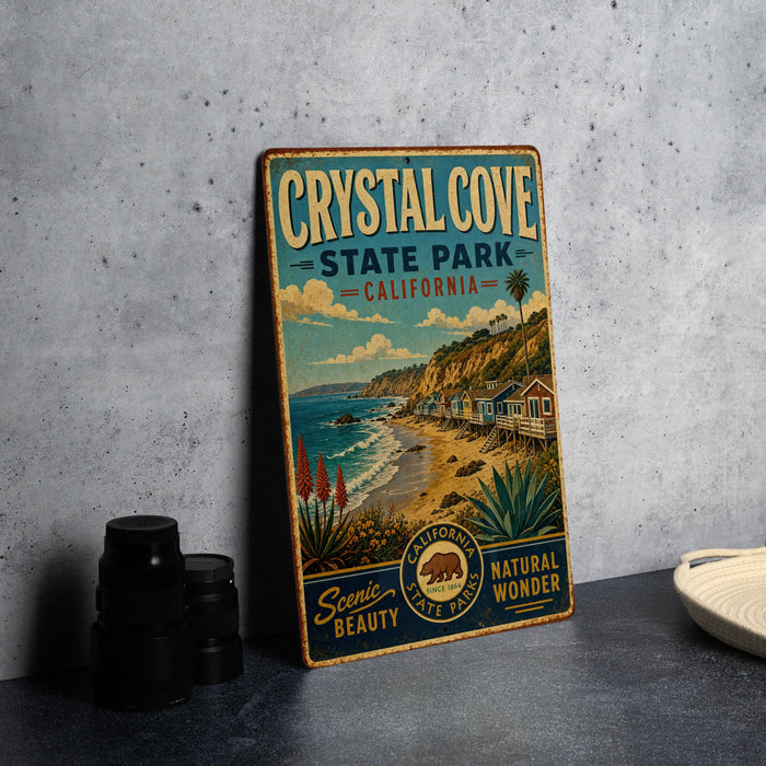 A vintage-style metal sign for Crystal Cove State Park, California, featuring a scenic beach landscape with palm trees and houses.