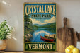 A vintage-style sign for Crystal Lake State Park in Vermont, featuring a scenic image of a lake surrounded by mountains and pine trees.