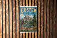 A vintage-style metal sign for Custer State Park in South Dakota, featuring a mountain landscape and a goat.