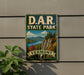 A vintage-style metal sign for Vermont State Park, featuring a scenic landscape with mountains, forests, and a lake.
