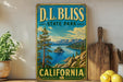 A vintage-style metal sign for D.L. Bliss State Park in California, featuring a scenic landscape with mountains, a lake, and pine trees.