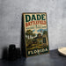 A vintage metal sign for Dade Battlefield Historic State Park in Florida, featuring an illustration of a cannon and a building, is displayed on a gray concrete surface.