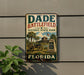 A vintage metal sign for Dade Battlefield Historic State Park in Florida, featuring a cannon and palm trees, is displayed on a wall.