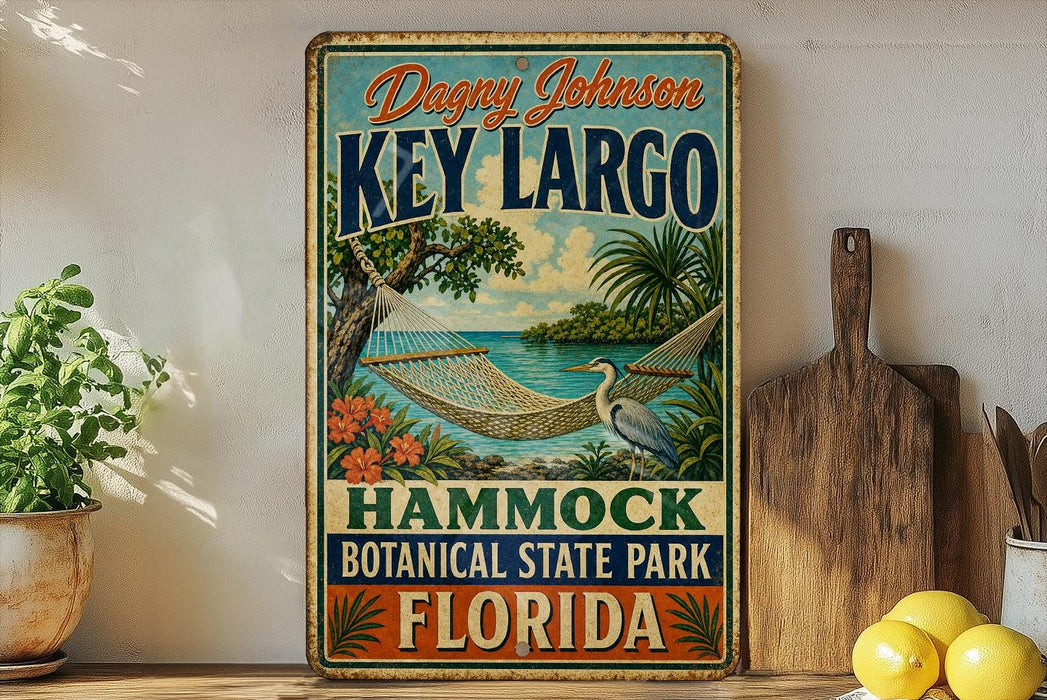 A vintage-style metal sign for "Key Largo" in the "Hammond Botanical State Park, Florida", featuring a hammock and tropical foliage.