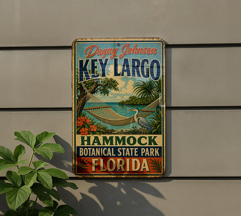 A vintage-style metal sign for Key Largo, Florida, featuring a hammock and tropical foliage, mounted on a wall.