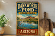 A vintage-style sign for Dankworth Pond State Park in Arizona, featuring a scenic landscape with a heron and a pond surrounded by mountains.