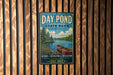 A vintage metal sign for Day Pond State Park in Connecticut, featuring a scenic image of a lake with a canoe, surrounded by pine trees and mountains.