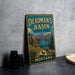 A vintage-style metal sign for Deadman's Basin State Park in Montana, featuring a scenic landscape with mountains, a lake, and a buffalo.