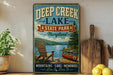 a vintage-style sign for Deep Creek Lake State Park in Maryland, with a scenic illustration of a lake, mountains, and a canoe.