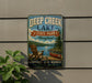 A vintage-style metal sign for Deep Creek Lake State Park in Maryland, featuring a scenic image of a lake, mountains, and a canoe.