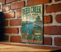 A vintage metal sign for Deer Creek State Park in Ohio, featuring a scenic illustration of a deer, a lake, and mountains.