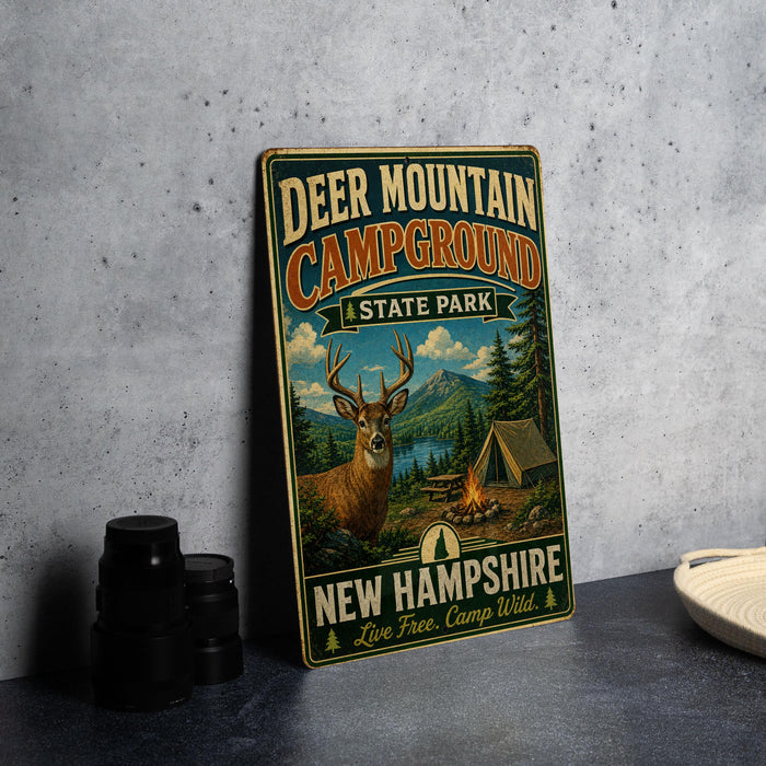 A vintage-style metal sign for Deer Mountain Campground, featuring a deer, a tent, and a campfire, with the text "DEER MOUNTAIN CAMPGROUND" and "NEW HAMPSHIRE" prominently displayed.